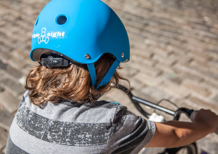 Child wearing a blue kids Triple Eight helmet on a bike.